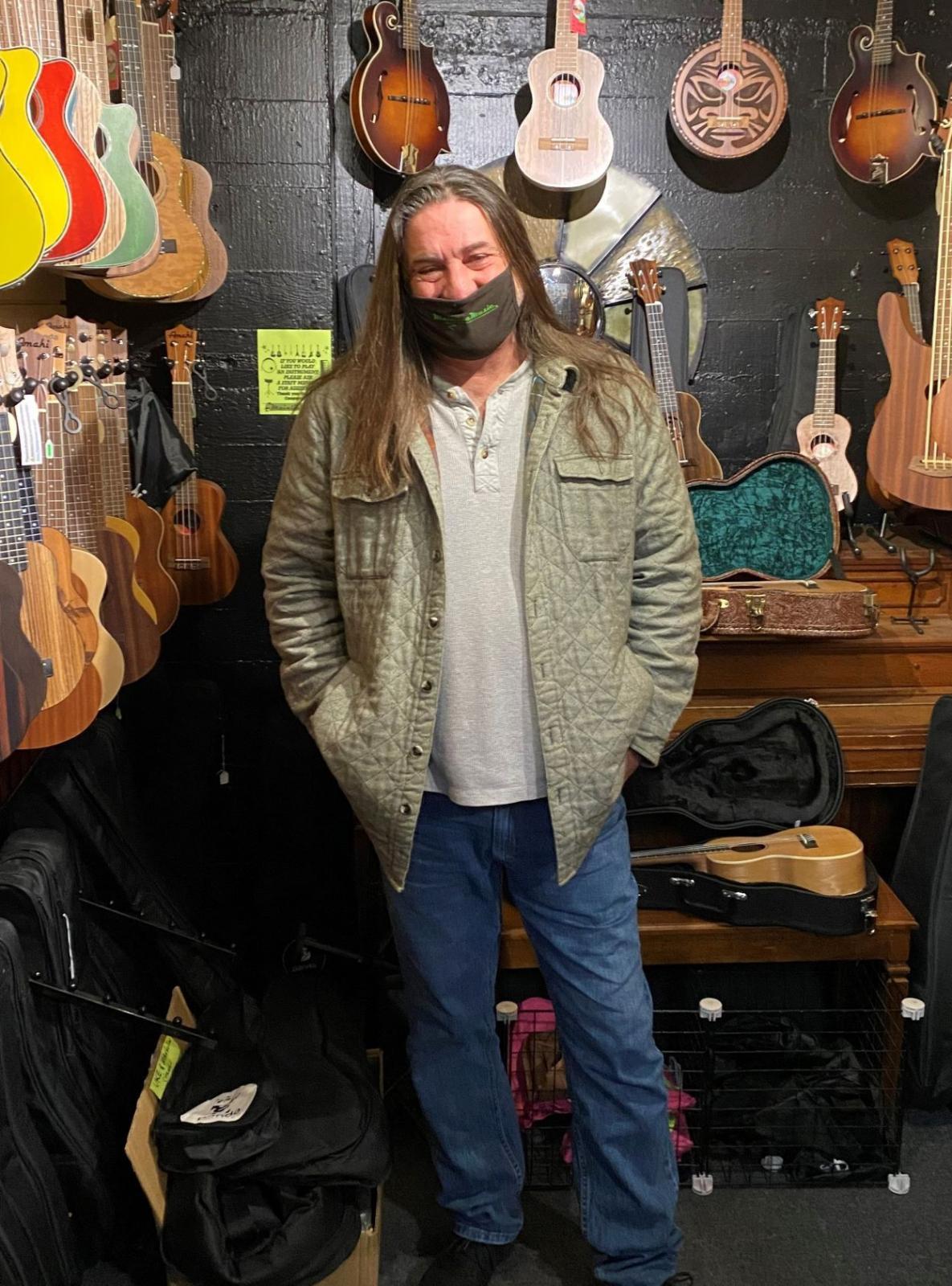 man wearing face mask standing in guitar store